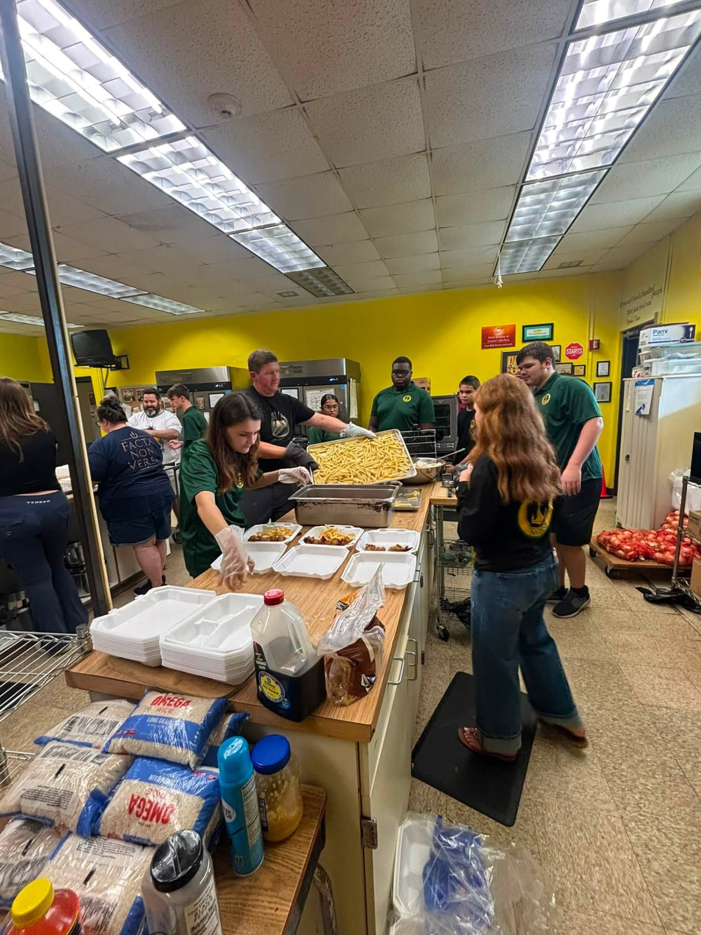 Volunteers preparing and packing hot meals in the kitchen during Team Mess Hall on August 28, 2026.