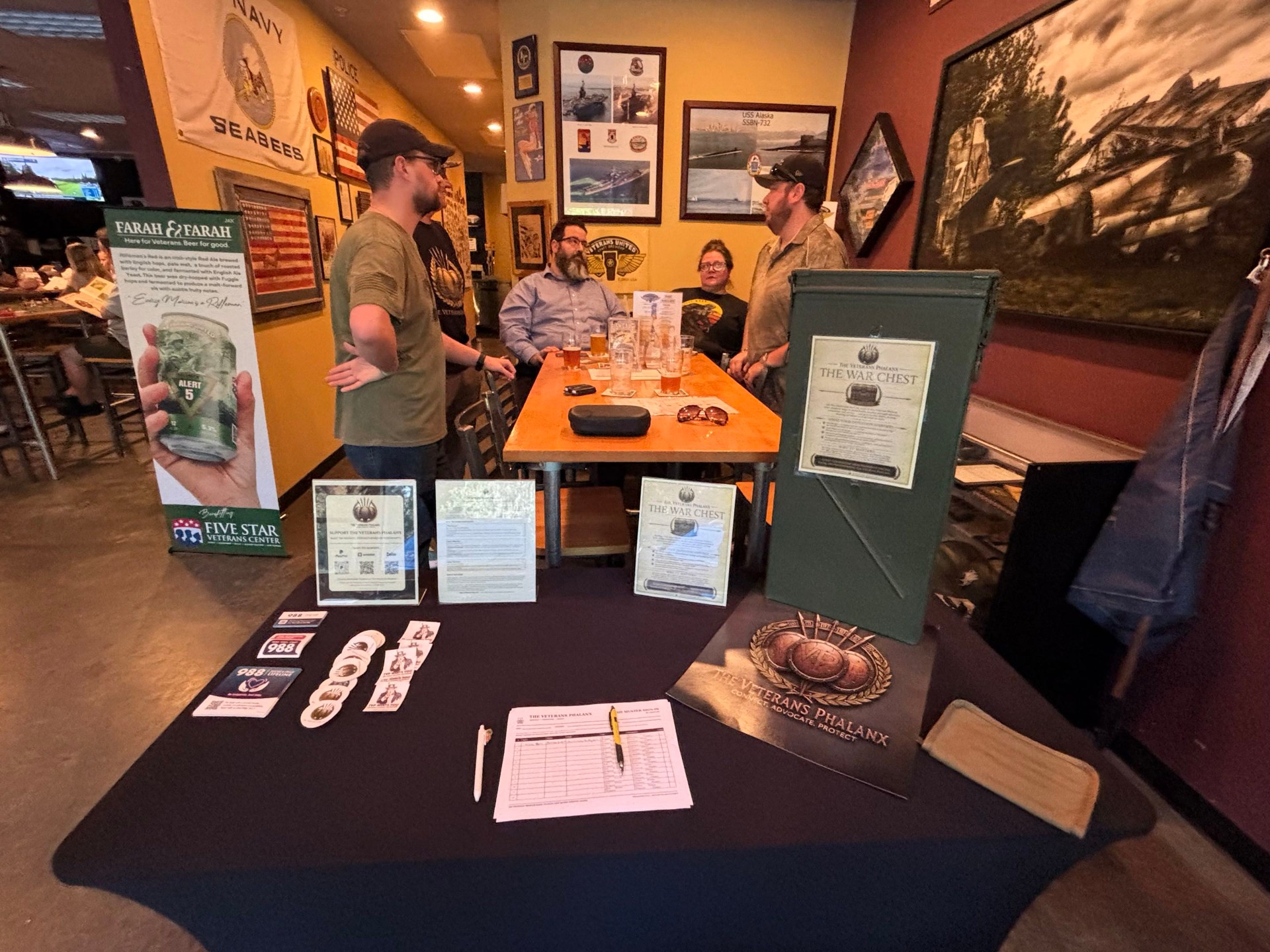 The Veterans Phalanx information table and attendees talking during The Muster.