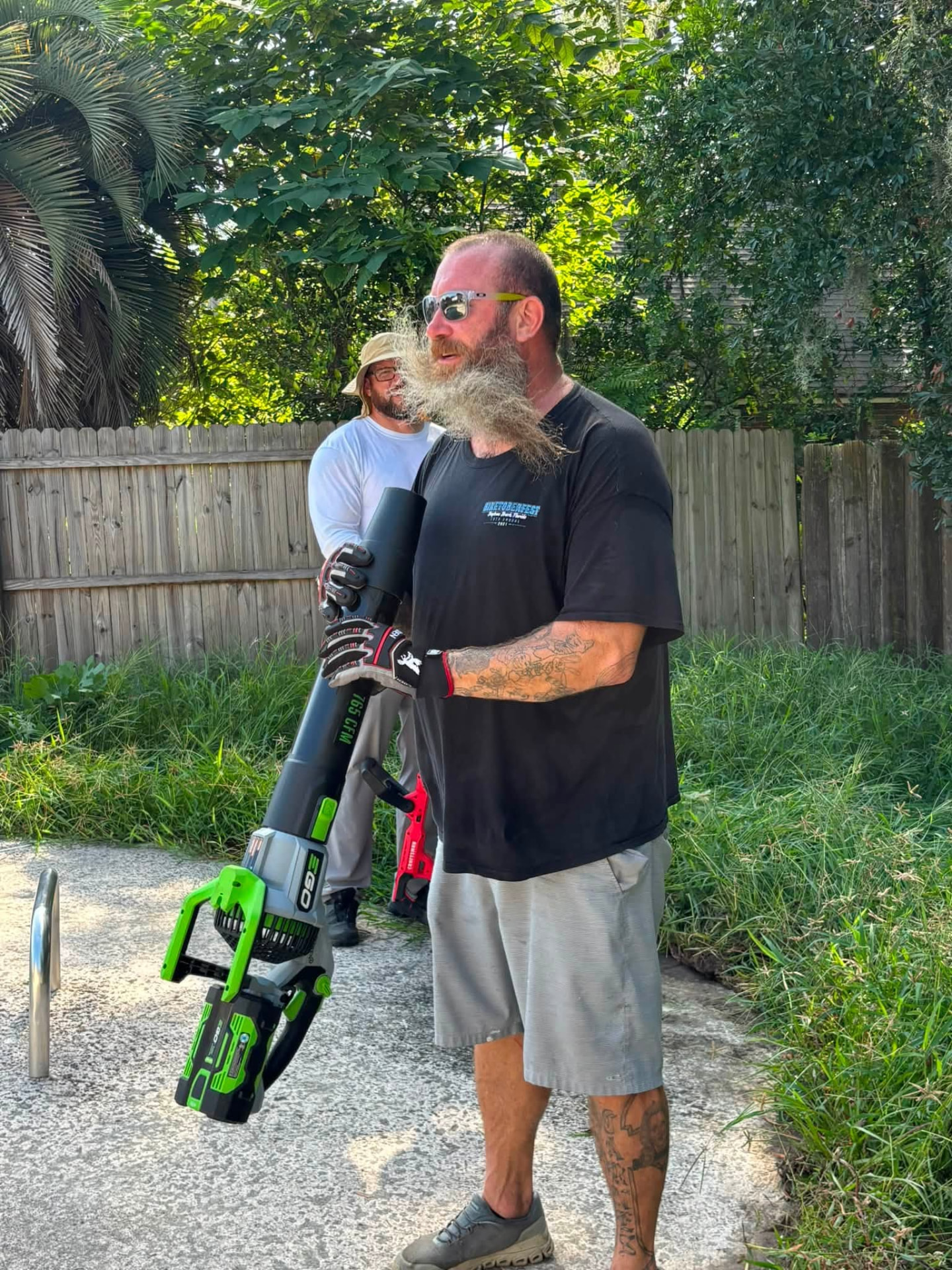 A volunteer carrying a leaf blower during a Next Objective: Homefront yard cleanup for a veteran household.