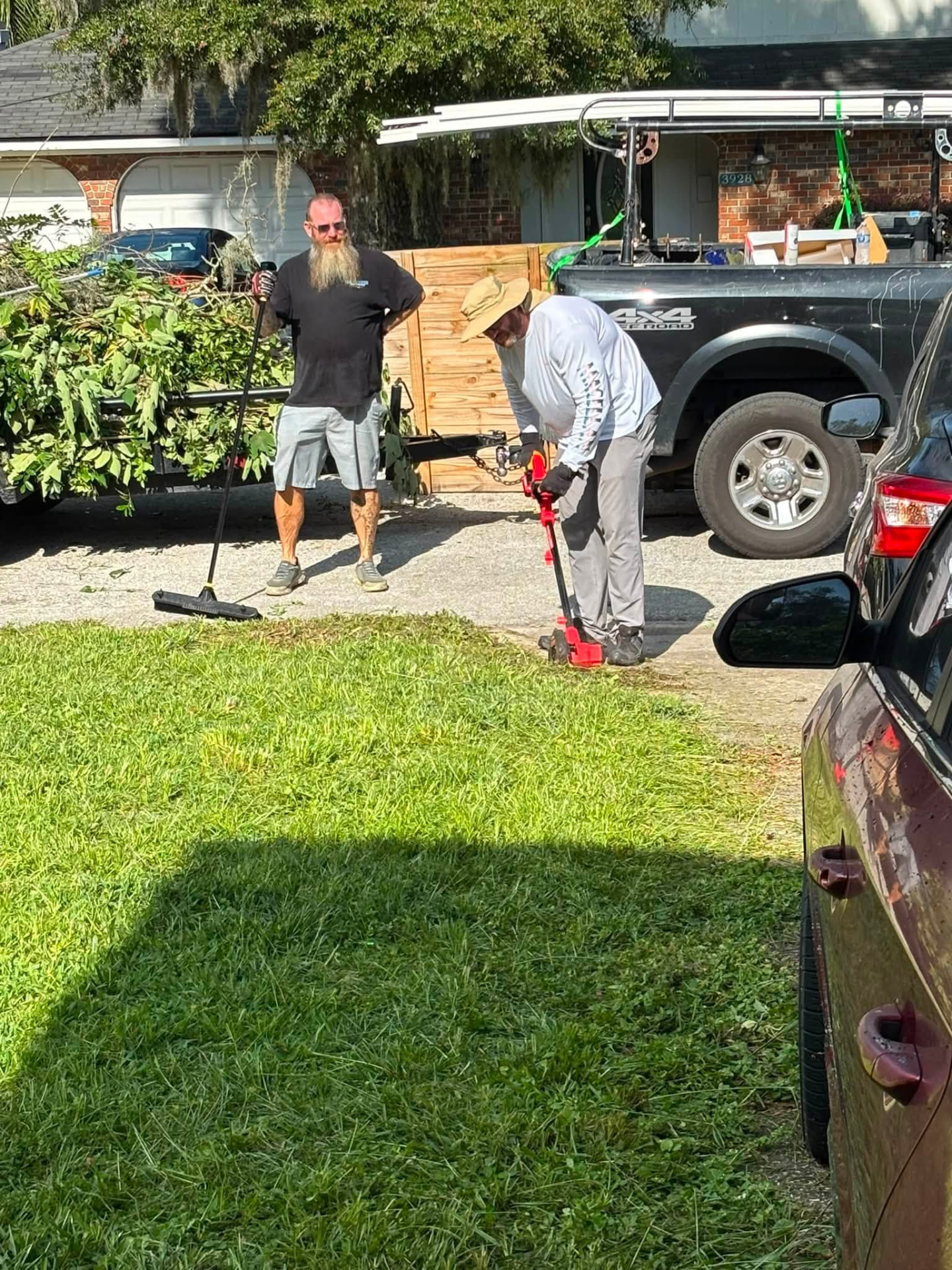 Volunteers edging the driveway and loading yard debris during a Next Objective: Homefront property cleanup.