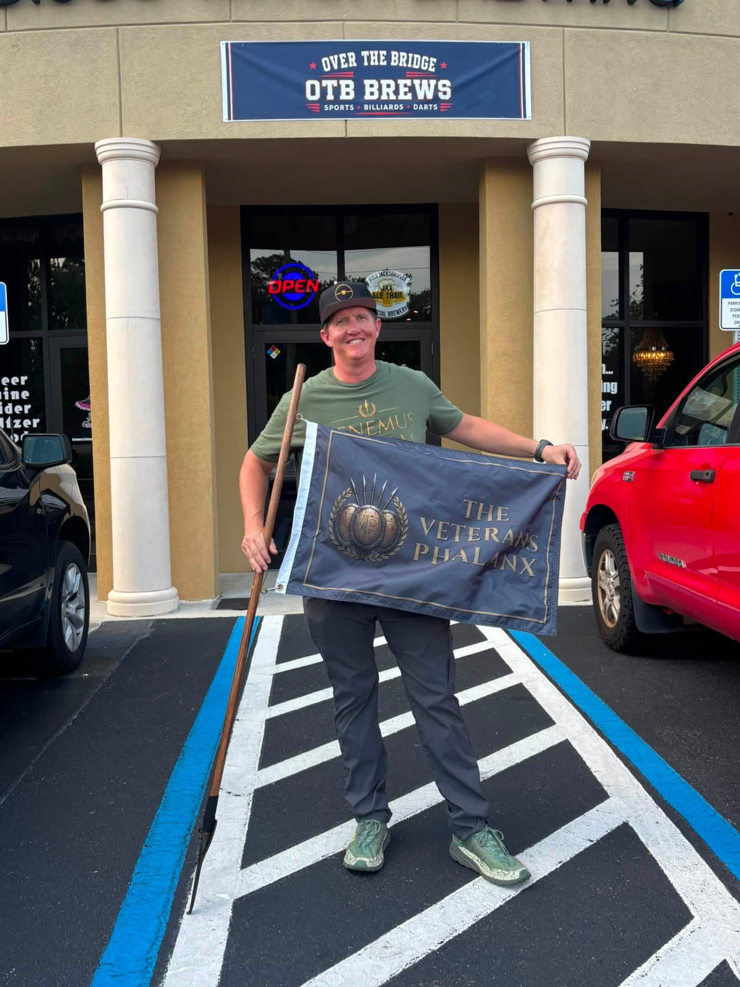 A Veterans Phalanx member holding The Veterans Phalanx Standard outside Over the Bridge Brews in Yulee before The Muster.