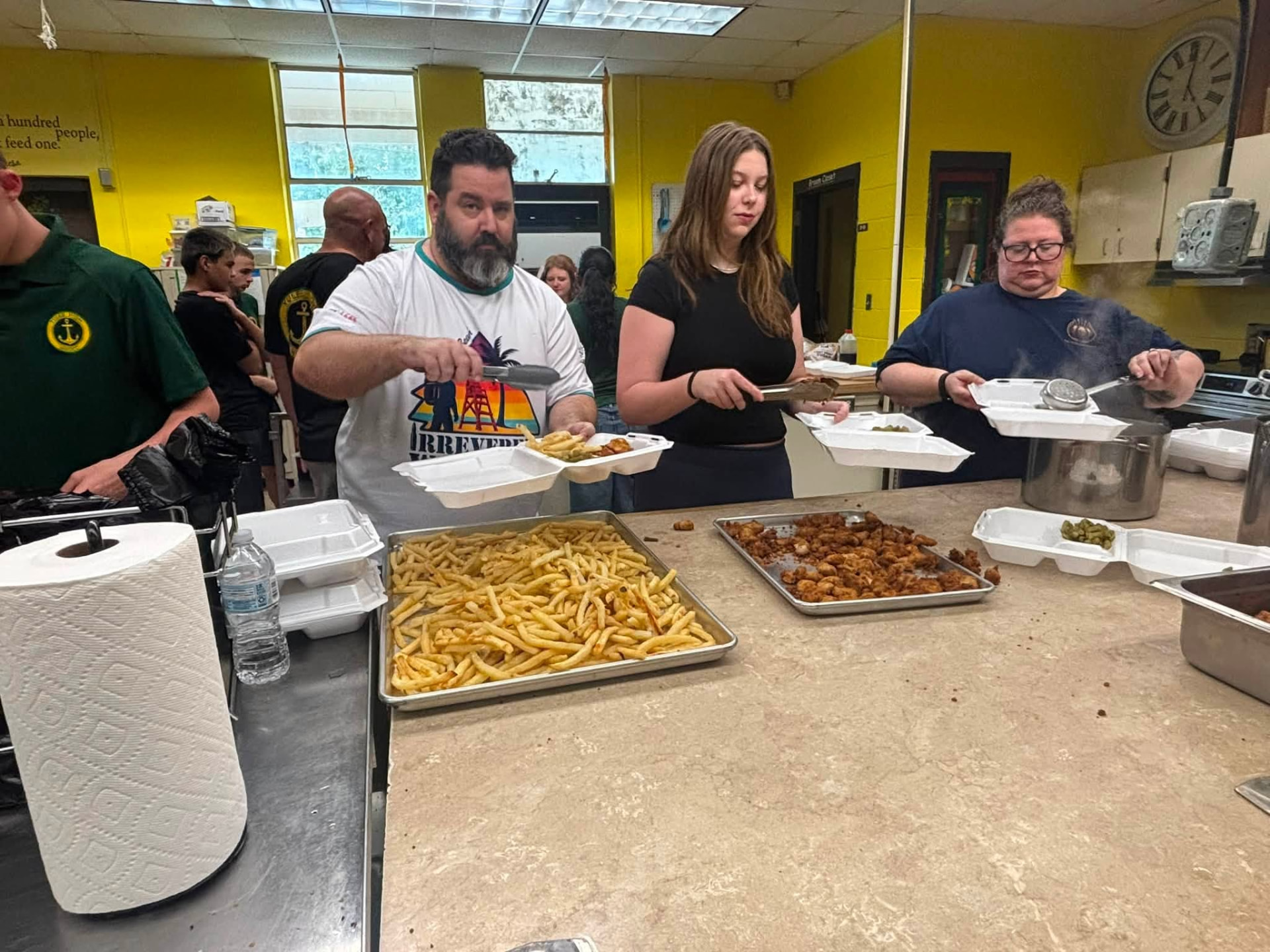 Volunteers filling meal containers along the serving line during Team Mess Hall on August 28, 2026.